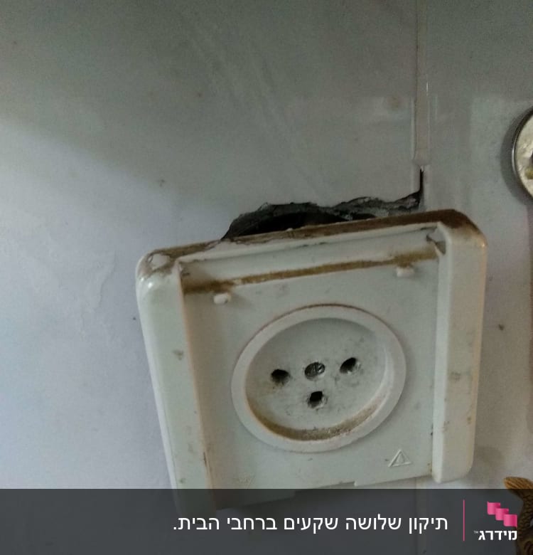 שקע חשמלי ישן עם סדקים בקיר